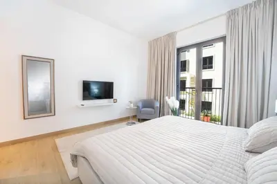 a white bedroom with a large bed and a tv at Stunning 2BR Apartment in Port De La Mer in Dubai