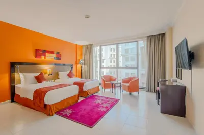 a hotel room with two beds and a flat screen tv at Icon Delux Hotel Apartments Al Barsha - Formerly Abidos in Dubai