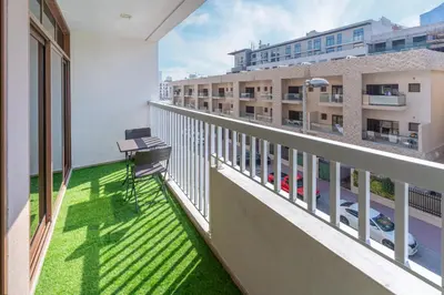 a balcony with green grass and a building at 1bd apt plus study I Close to mall I Fast wi-fi in Dubai
