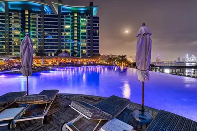 a swimming pool with two chairs and umbrellas at 2 Bedroom App with private beach and infinity pool in Dubai