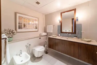 a bathroom with a sink and a toilet and a mirror at 2 Bedroom App with private beach and infinity pool in Dubai