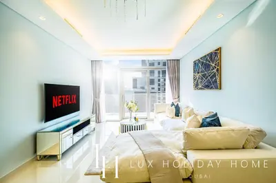 a living room with a couch and a tv at LUX Paramount Burj View Business Bay in Dubai