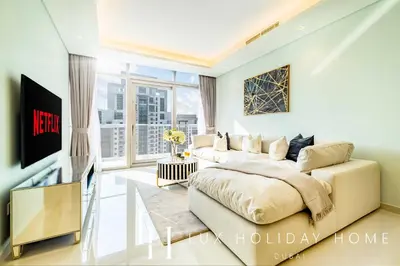 a living room with a bed and a television at LUX Paramount Burj View Business Bay in Dubai