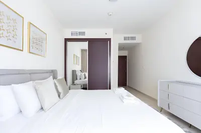 a white bedroom with a large bed with white pillows at High Floor Elegance,Prime Location-Close to tram in Dubai