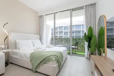a bedroom with a white bed and a large window at Very Cozy & Relaxing Studio in JVC in Dubai