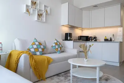a living room with a white couch and a table at Brand New & Modern Studio in JVC in Dubai