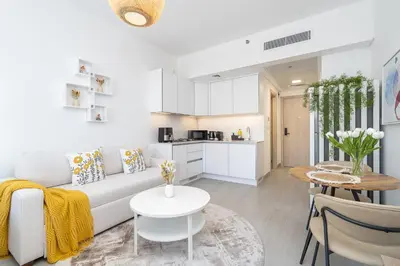 a living room with a white couch and a table at Brand New Vibrant Studio in JVC in Dubai