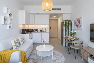 a living room and kitchen with a couch and a table at Brand New Vibrant Studio in JVC in Dubai