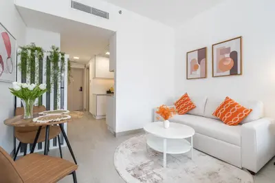 a living room with a white couch and a table at Bright & Modern Studio in JVC in Dubai