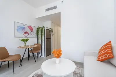 a living room with a white table and chairs at Bright & Modern Studio in JVC in Dubai