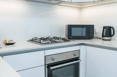 a kitchen with a stove top oven next to a microwave at Bright & Modern Studio in JVC in Dubai