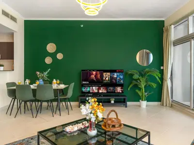 a living room with a green wall at Relax & Unwind in This Cozy 2BR Apartment in Dubai