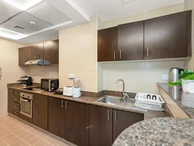 a kitchen with brown cabinets and a sink and a counter at Relax & Unwind in This Cozy 2BR Apartment in Dubai