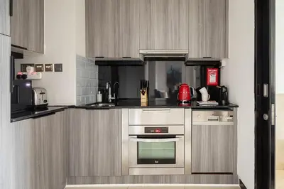 a kitchen with stainless steel appliances and gray cabinets at Frank Porter - Emaar Residences Dubai Marina in Dubai