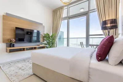 a bedroom with a large white bed and a large window at Full Golf View Studio in Damac Hills - Host & Stay in Dubai
