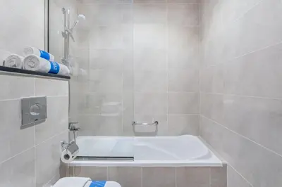 a bathroom with a shower with a tub and a toilet at Full Golf View Studio in Damac Hills - Host & Stay in Dubai