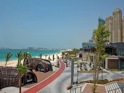 a street with benches and the beach and buildings at 2BR Jumeirah Beach front Residence in Dubai