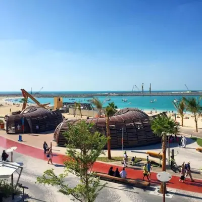 a group of people walking on a beach near the water at 2BR Jumeirah Beach front Residence in Dubai