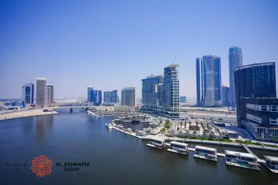 a river with boats in a city with tall buildings at Alashrafia Saray - Superb 1 BR in Canal Views in Dubai
