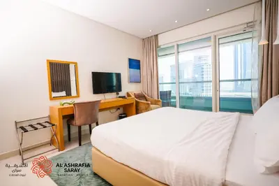 a hotel room with a bed and a desk and a television at Alashrafia Saray - Superb 1 BR in Canal Views in Dubai