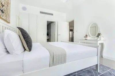 a white bedroom with a white bed and a mirror at Frank Porter - Al Ghozlan 4 in Dubai