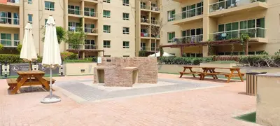 a patio with a brick grill and tables and an umbrella at Frank Porter - Al Ghozlan 4 in Dubai