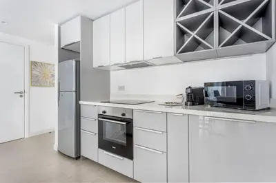 a white kitchen with white cabinets and a refrigerator at Frank Porter - Al Ghozlan 4 in Dubai