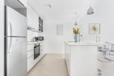 a kitchen with white cabinets and a refrigerator at Frank Porter - Al Ghozlan 4 in Dubai