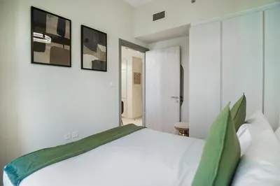a bedroom with a large white bed with green pillows at EasyGo - Affordable 1br Close to Public Transit - Zad-13 in Dubai