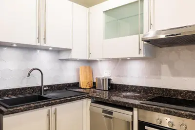 a kitchen with white cabinets and a sink at Apartment in Golden Mile with access to Fairmont in Dubai