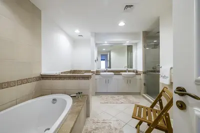a bathroom with two sinks and a tub and two mirrors at Apartment in Golden Mile with access to Fairmont in Dubai
