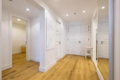 an empty hallway with white walls and wood floors at Apartment in Golden Mile with access to Fairmont in Dubai