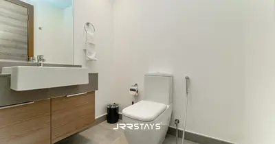 a bathroom with a white toilet and a sink at Stylish Studio - Panoramic Pool View - JVC in Dubai