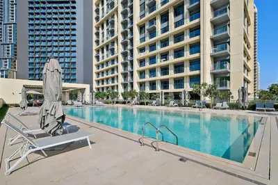 a pool with a chair and an umbrella next to a building at Silkhaus Burj Royale 1BDR with balcony in Downtown in Dubai