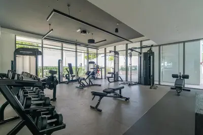 a gym with treadmills and machines in a room with windows at Seaside Serenity: 1-BR Apartment with Beach Access in Dubai