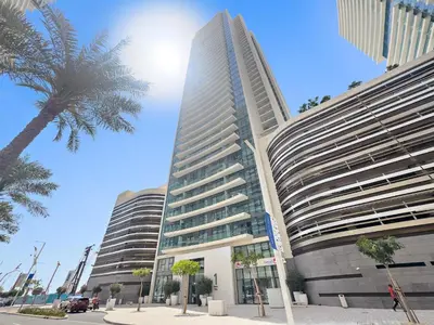 a tall building with a palm tree in front of it at Seaside Serenity: 1-BR Apartment with Beach Access in Dubai