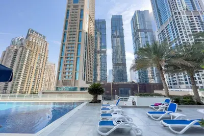a pool with chaise lounge chairs in a city at GuestReady - Lux interiors in Dubai Marina in Dubai