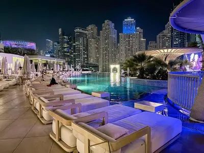 a pool with lounge chairs and a city skyline at night at Breathtaking view studio – Address Dubai Marina in Dubai