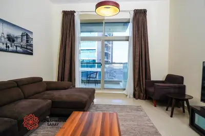 a living room with a couch and a table and a window at Alashrafia Saray - Adorable 1BR in Sports City in Dubai