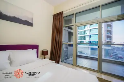 a bedroom with a bed and a large window at Alashrafia Saray - Adorable 1BR in Sports City in Dubai