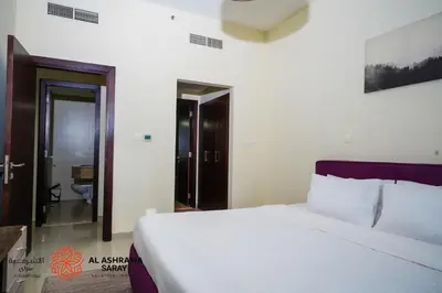a bedroom with a large white bed and a bathroom at Alashrafia Saray - Adorable 1BR in Sports City in Dubai