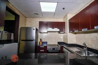a kitchen with wooden cabinets and a stainless steel refrigerator at Alashrafia Saray - Adorable 1BR in Sports City in Dubai