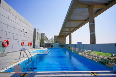a swimming pool on the roof of a building at Alashrafia Saray - Adorable 1BR in Sports City in Dubai