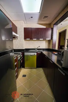 a kitchen with brown cabinets and a yellow dishwasher at Alashrafia Saray - Adorable 1BR in Sports City in Dubai