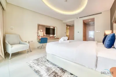 a bedroom with a large white bed and a chair at Sophisticated 2BR at DAMAC Towers by Paramount A Business Bay by Deluxe Holiday Homes in Dubai