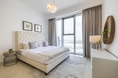 a white bedroom with a bed and a large window at Creek View Apartment in Creek Harbour in Dubai