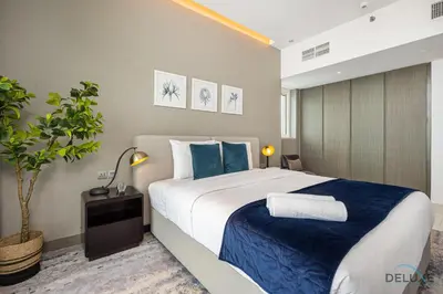 a bedroom with a large bed with blue pillows at Special Offer Elegant Studio with Iconic Canal Views by Deluxe Holiday Homes in Dubai