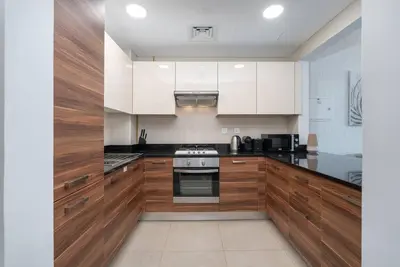 a kitchen with wooden cabinets and a stove top oven at Lush Tropical Getaway in Dubai Marina in Dubai