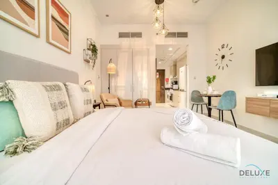 a large white bed in a room with chairs at Picturesque Studio at Carson A DAMAC Hills Dubailand by Deluxe Holiday Homes in Dubai