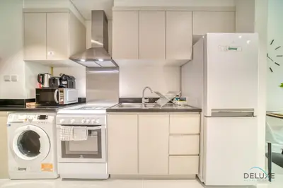 a kitchen with white cabinets and a washer and dryer at Picturesque Studio at Carson A DAMAC Hills Dubailand by Deluxe Holiday Homes in Dubai